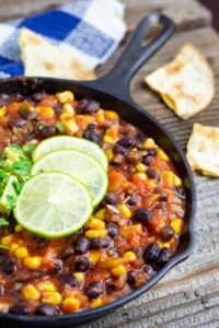 A skillet of been chili topped with lime slices.