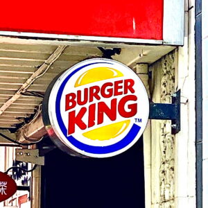 A Burger King sign hanging off the side of a building.