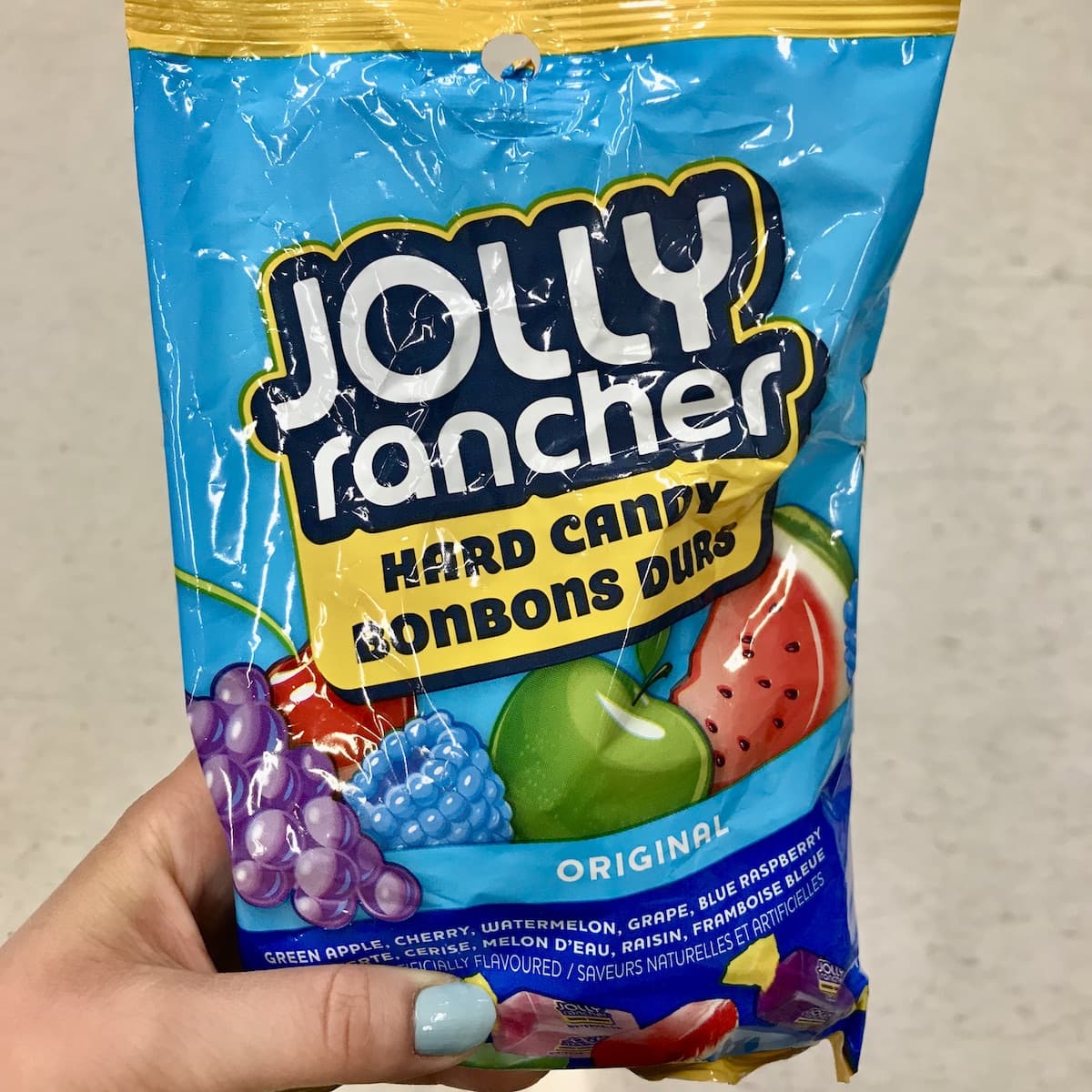 A hand holding a bag of Jolly Rancher Hard Candy.