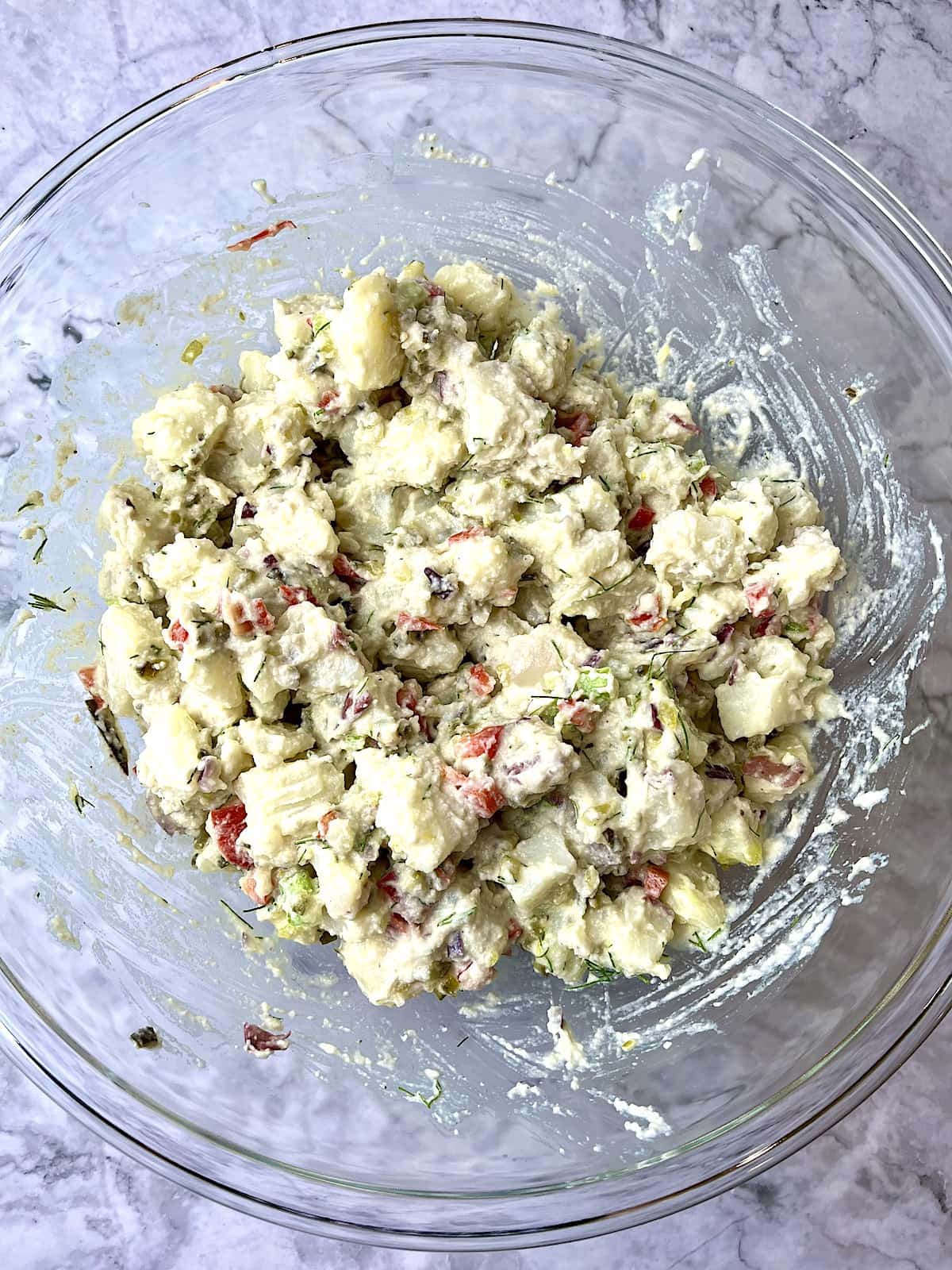 Potato salad with a creamy vegan dressing mixed in a large glass bowl.