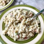 A plate of creamy macaroni salad with a fork in it.