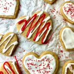 Numerous heart-shaped cookies decorated for Valentine's Day with red and white icing.