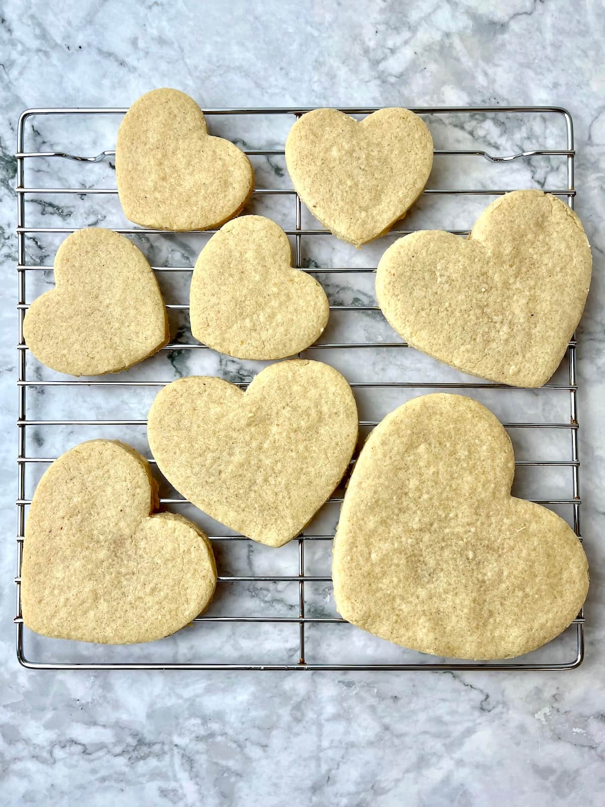 A cooling rack with heart-shaped sugar cookies on it.