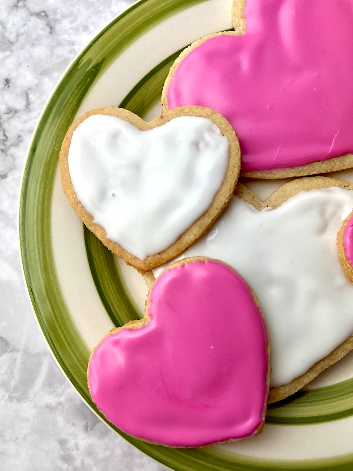 A plate of pink and white heart-shaped vegan sugar cookies.