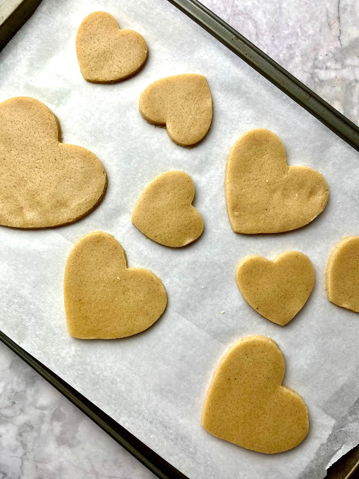 A baking tray of unbaked heart-shaped sugar cookies.