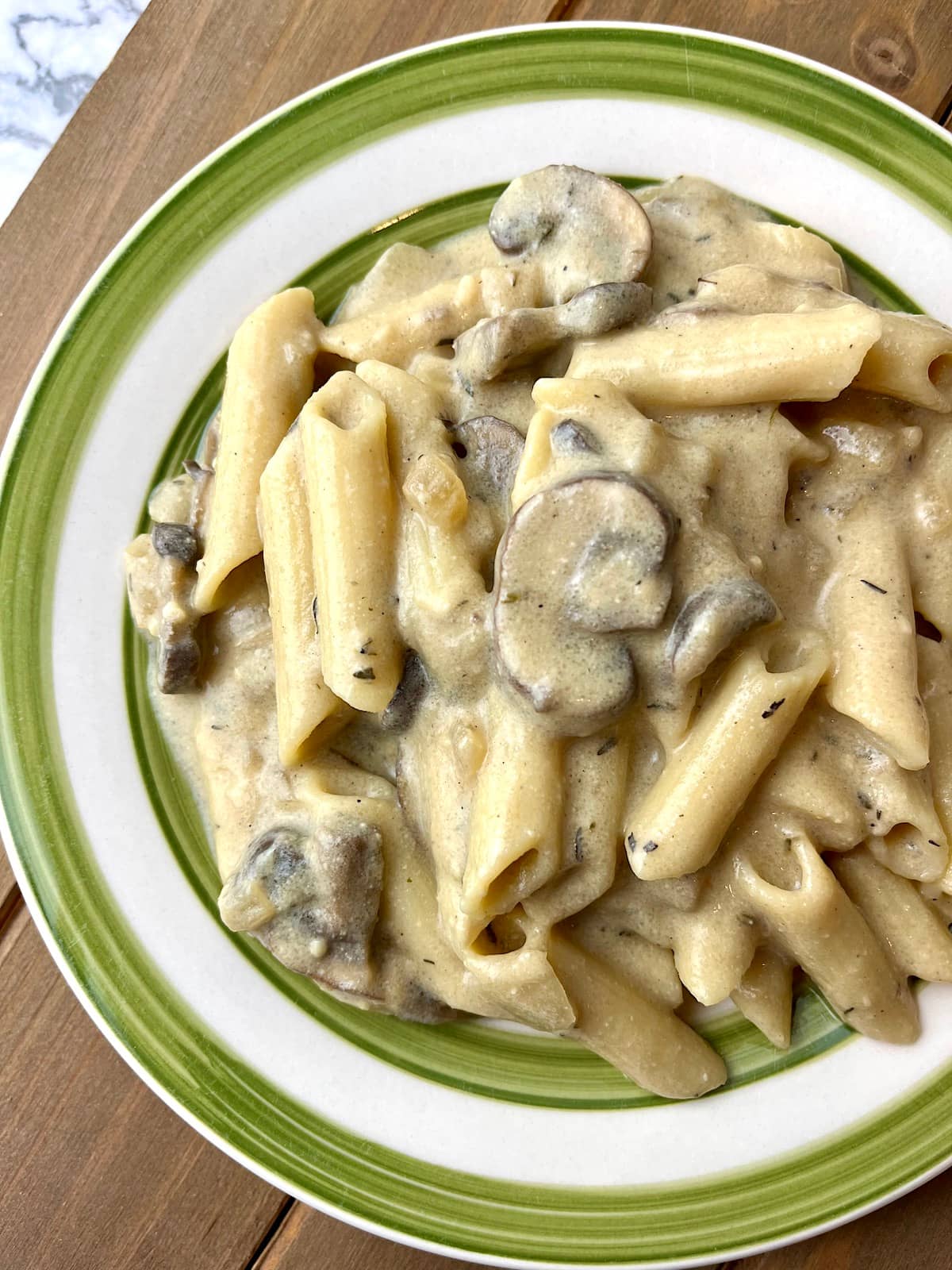 A plate of vegan mushroom stroganoff with penne pasta.