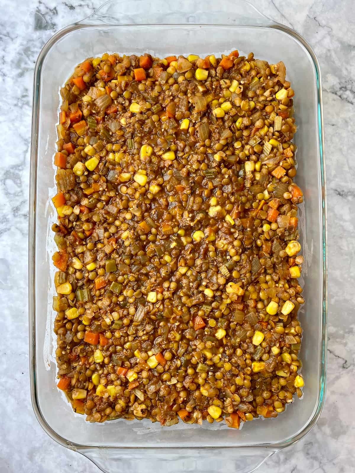A large dish with a lentil shepherd's pie filling in it.