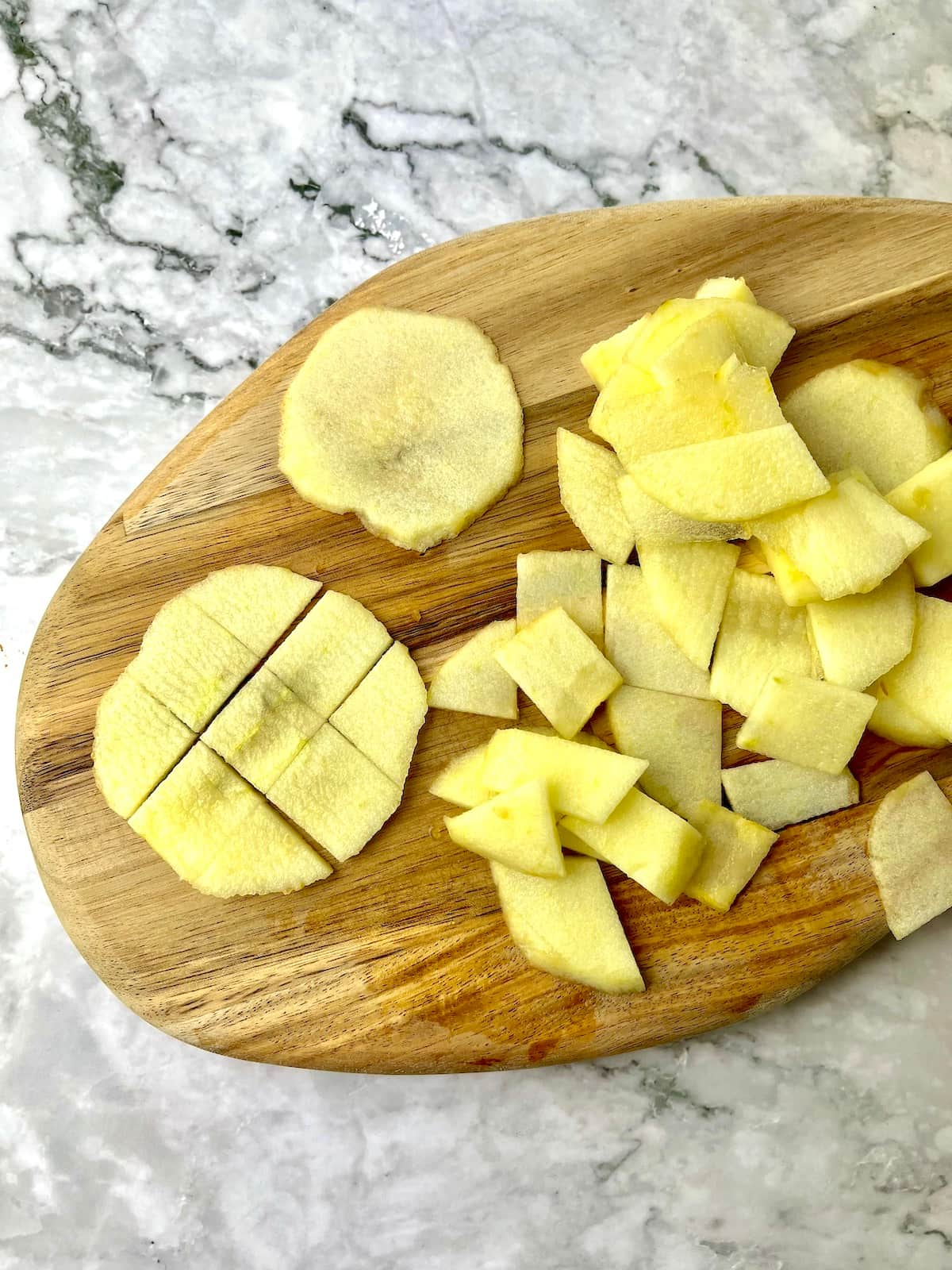 Thinly sliced pieces of apple on a wooden cutting board.