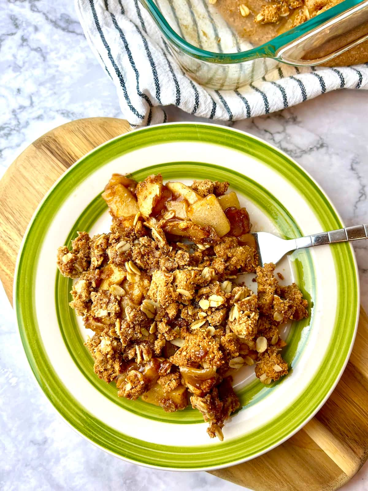 A plate of peanut butter apple crisp sitting on a wooden cutting board.