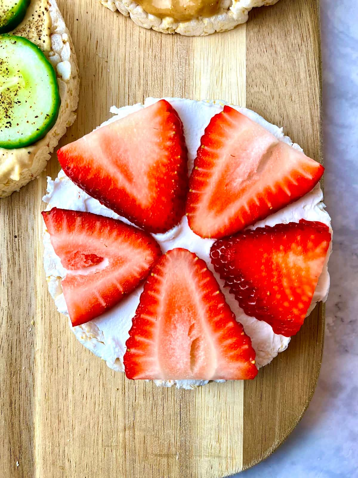 A rice cake topped with vegan cream cheese and strawberry slices.