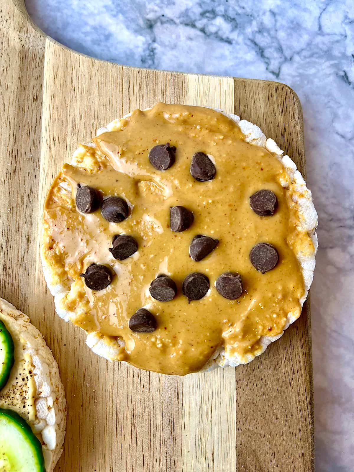 A rice cake topped with peanut butter and vegan chocolate chips.