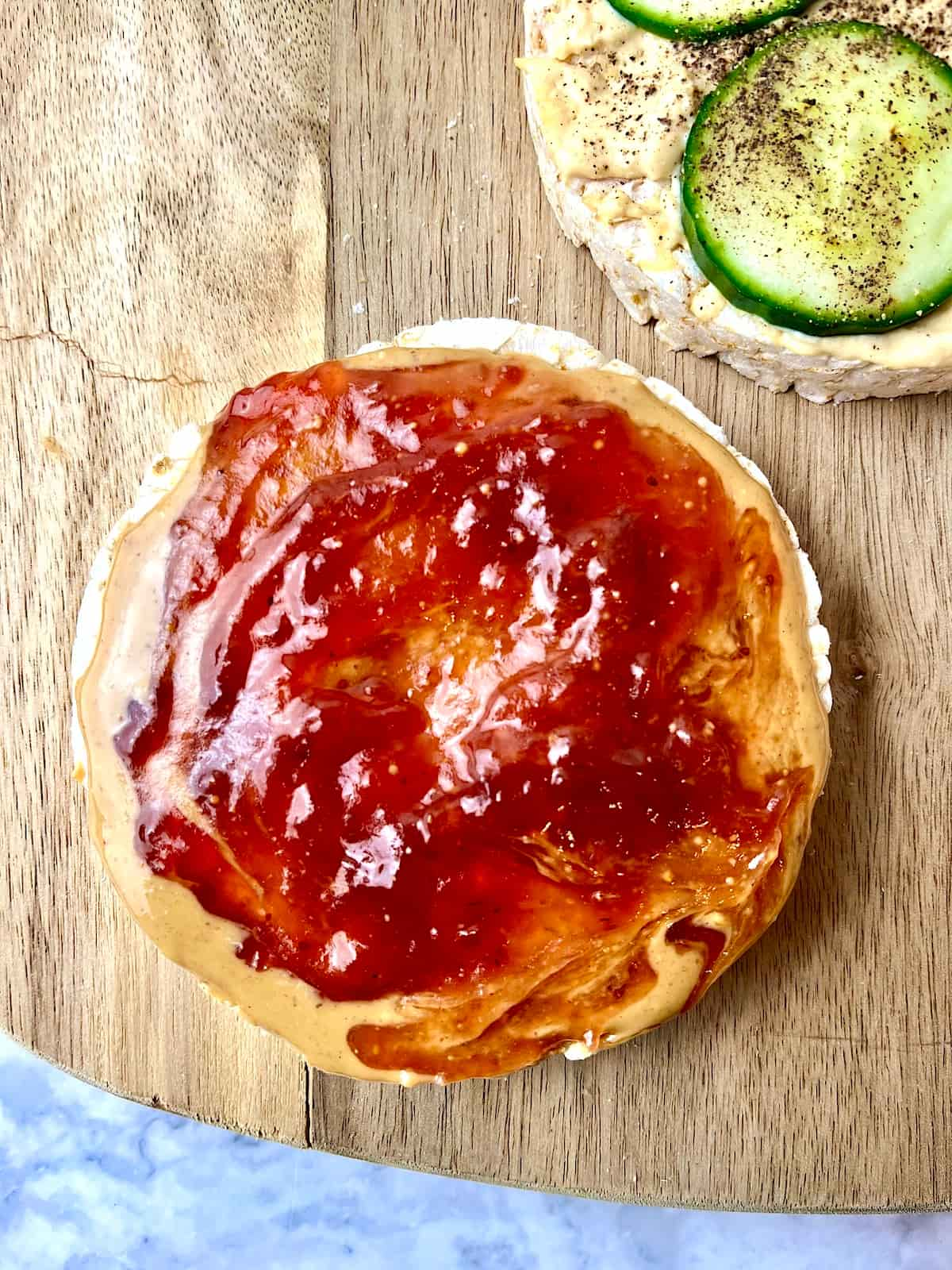 A rice cake topped with peanut butter and strawberry jam.