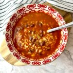 A bowl of salsa soup with rice and beans.