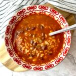 A bowl of salsa soup with rice and black beans.