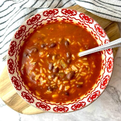 A bowl of salsa soup with rice and black beans.