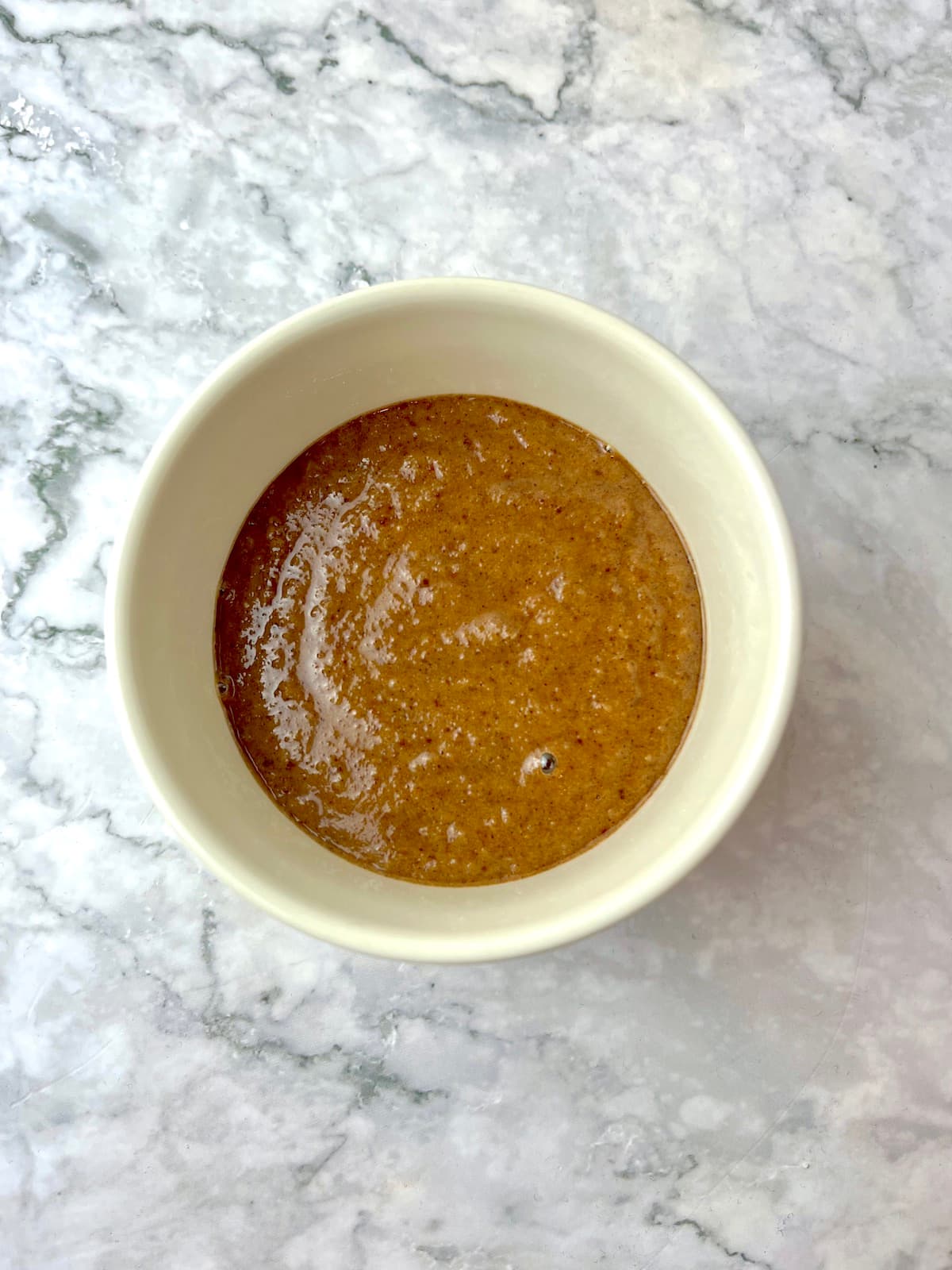 Cinnamon mug cake batter in a white ramekin.