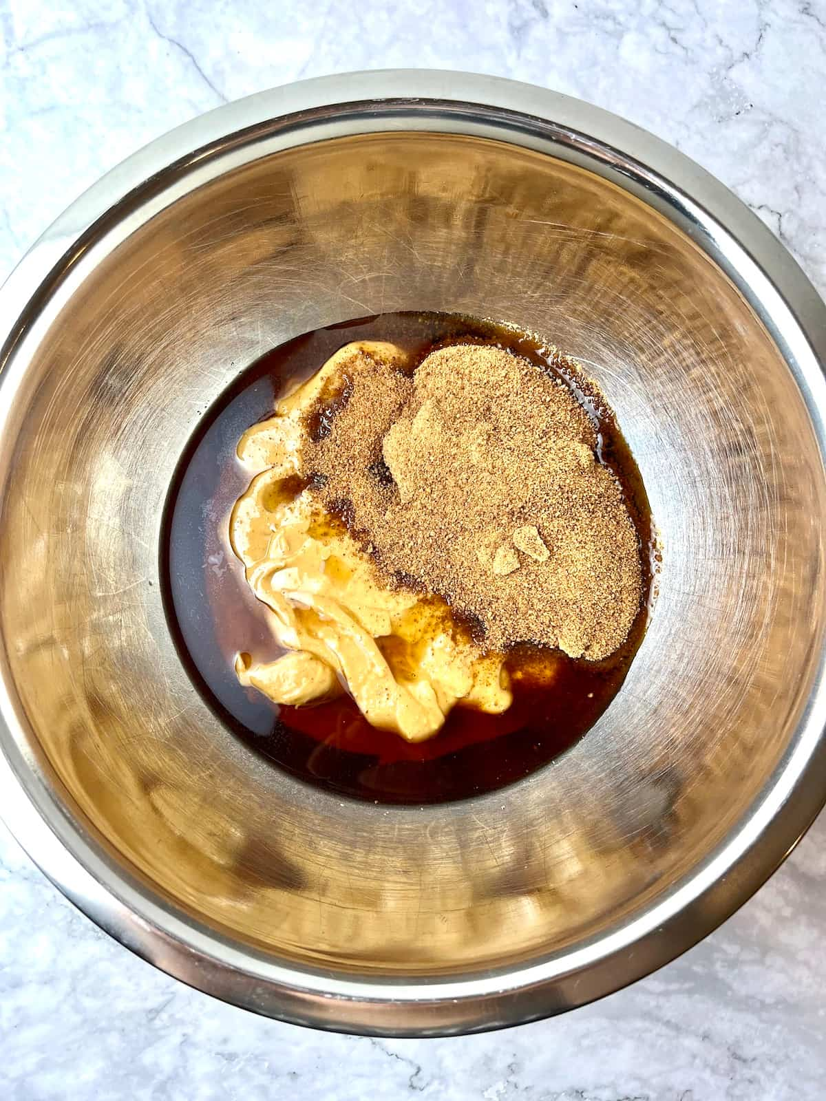 Peanut butter, maple syrup, and coconut sugar in a mixing bowl.