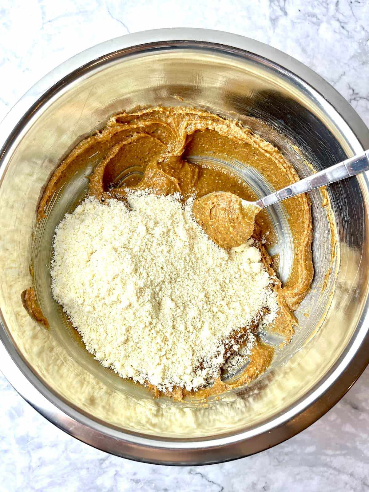 Peanut butter cookie ingredients with almond flour on top in a mixing bowl.