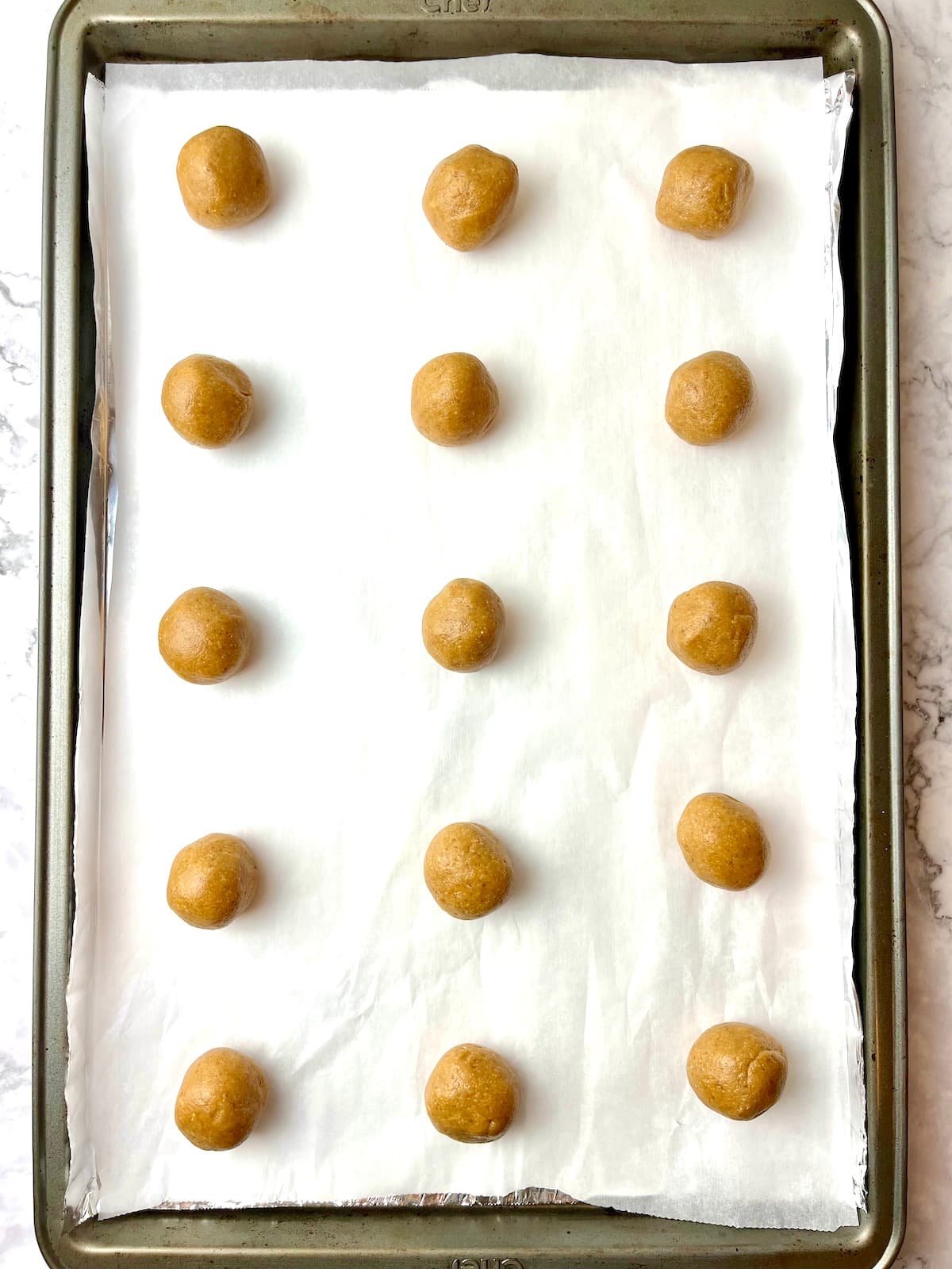 Peanut butter cookie dough balls on a baking sheet.