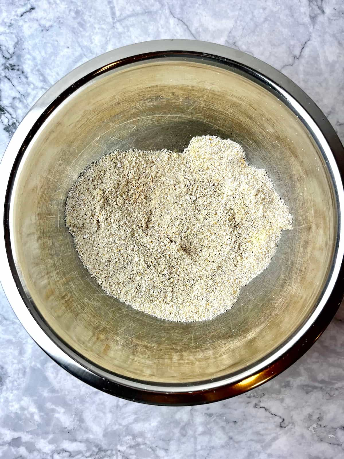 Almond flour and oat flour in a stainless steel mixing bowl.