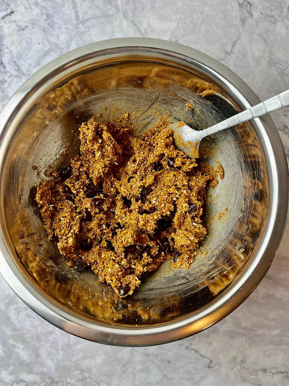 Almond butter cookie dough with chocolate chips in a mixing bowl.