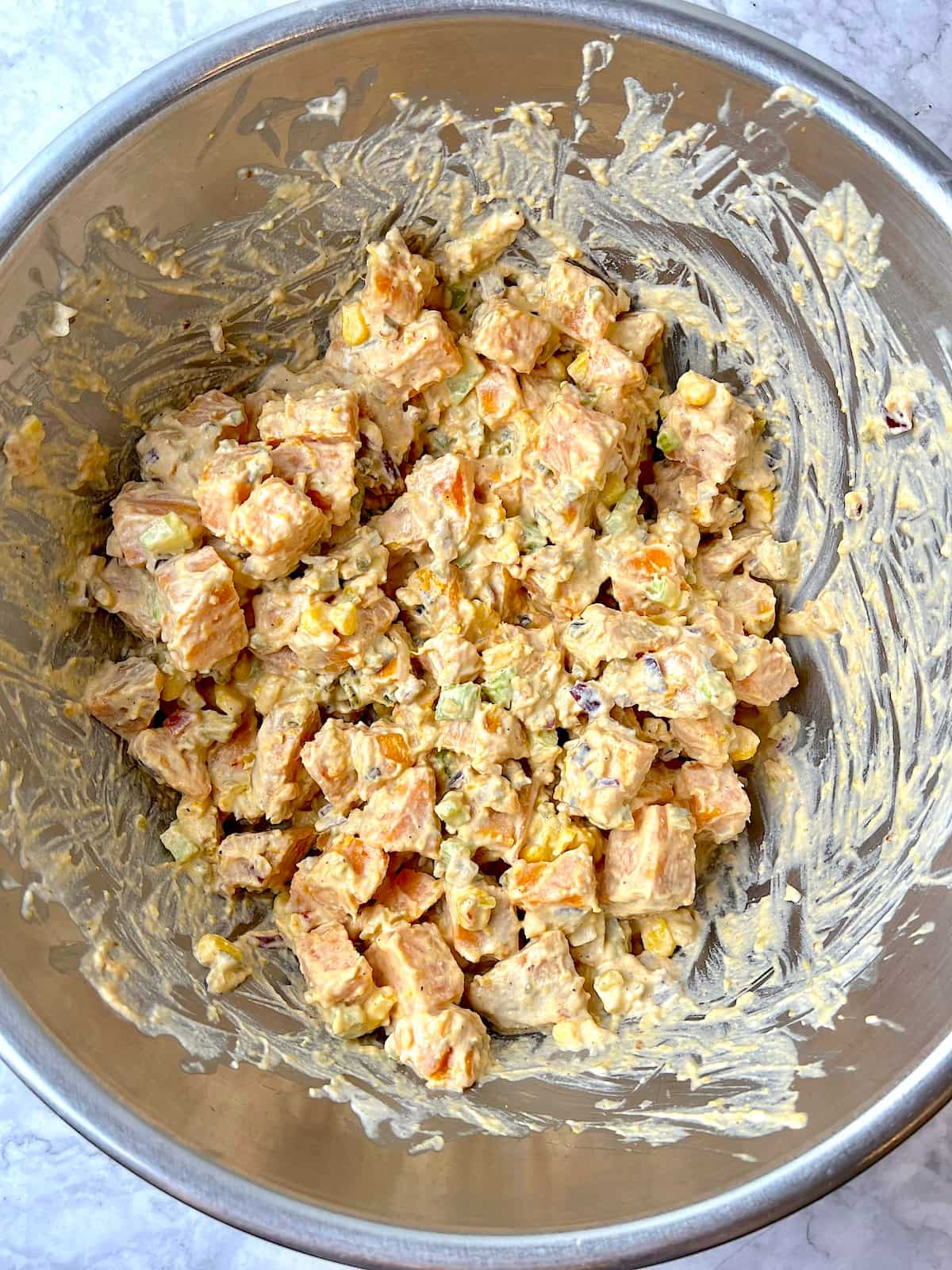 Creamy vegan sweet potato salad in a stainless steel mixing bowl.