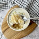 A spoonful of a vegan vanilla mug cake with frosting and sprinkles.