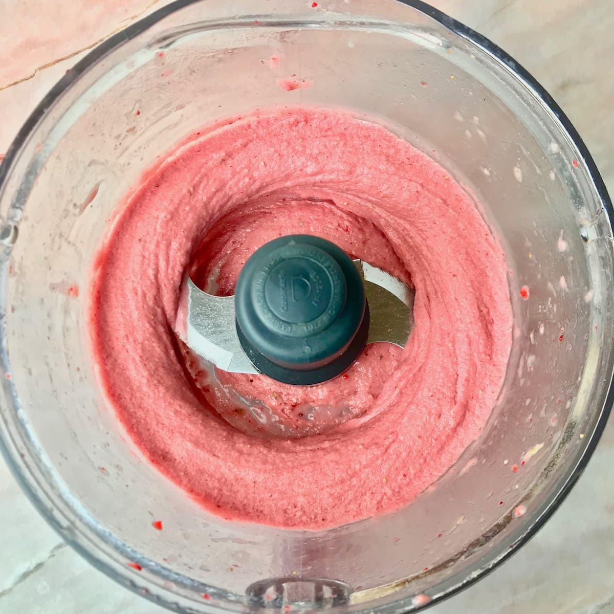 A strawberry and banana smoothie bowl in a food processor.